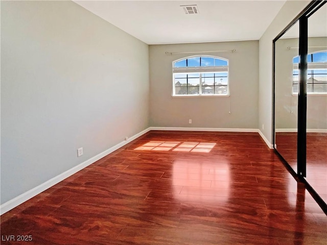 unfurnished room with visible vents, baseboards, and wood finished floors