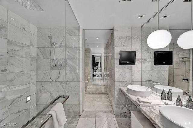 full bathroom featuring a sink, tile walls, a stall shower, and double vanity