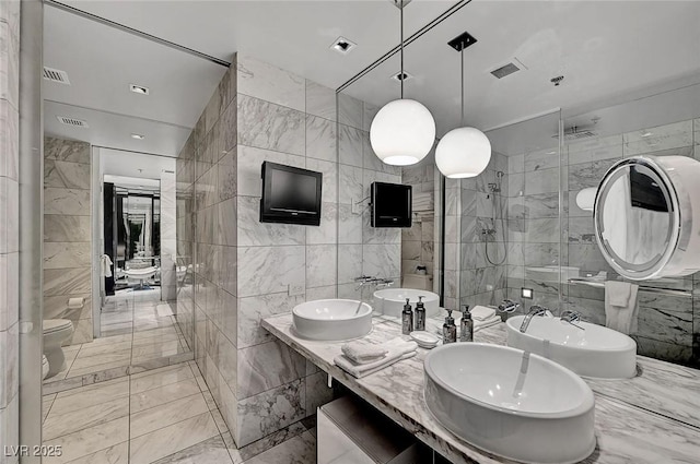 full bath featuring a sink, visible vents, marble finish floor, and tile walls