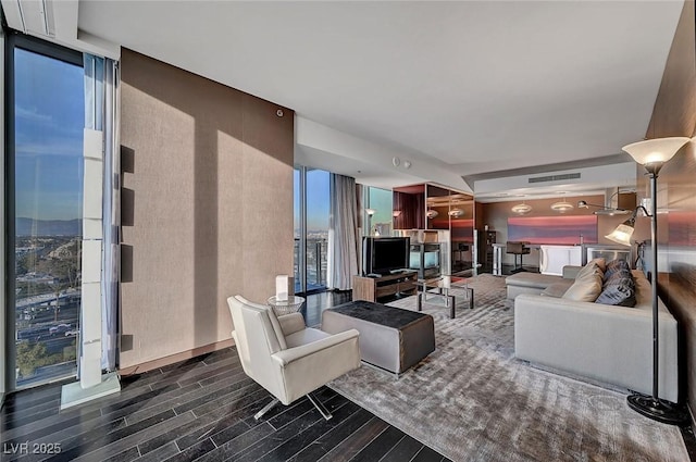 living area featuring floor to ceiling windows, wood finished floors, and visible vents