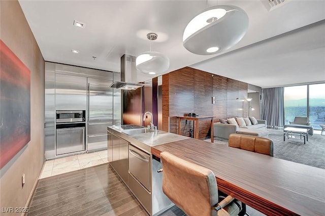 kitchen with visible vents, modern cabinets, a sink, island range hood, and a wall of windows