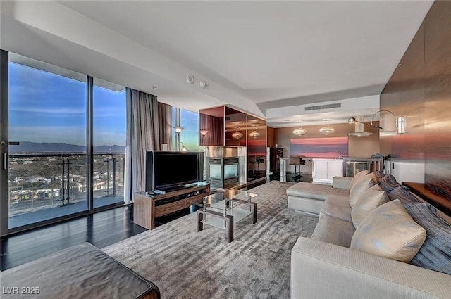 living area with visible vents, wood finished floors, and floor to ceiling windows