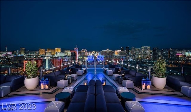 patio at night with an outdoor living space, a balcony, and a view of city lights