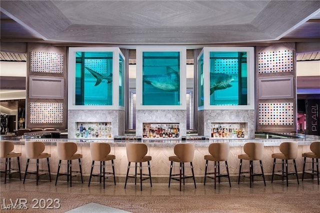 bar with decorative backsplash, speckled floor, and a community bar