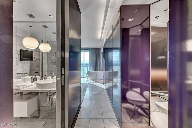 bathroom with a sink, marble finish floor, and tile walls