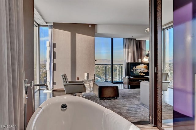 full bath featuring wood finished floors, a freestanding bath, and expansive windows