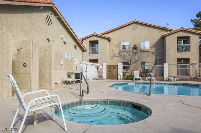 pool featuring a hot tub, a patio, and fence