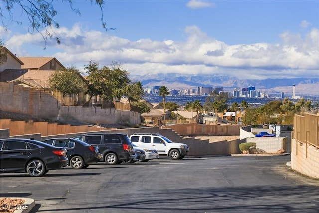 uncovered parking lot featuring a mountain view and fence