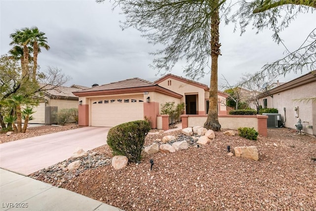 mediterranean / spanish house featuring an attached garage, central air condition unit, a tile roof, stucco siding, and driveway