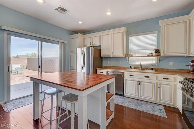 kitchen with visible vents, dark wood finished floors, butcher block counters, stainless steel appliances, and a sink