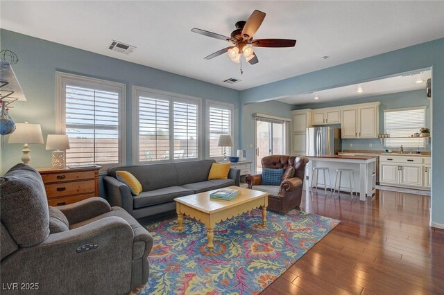 living area with visible vents, wood-type flooring, and plenty of natural light