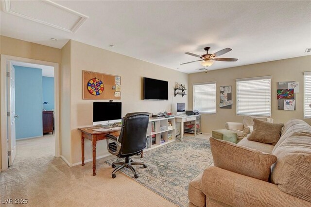 office with a ceiling fan, visible vents, baseboards, attic access, and light carpet