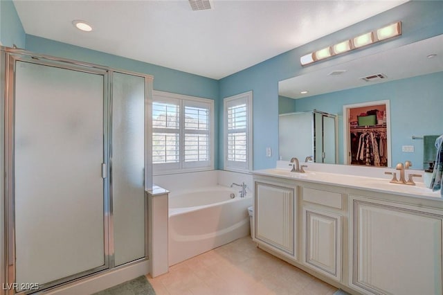 bathroom featuring a sink, a stall shower, a spacious closet, and a bath