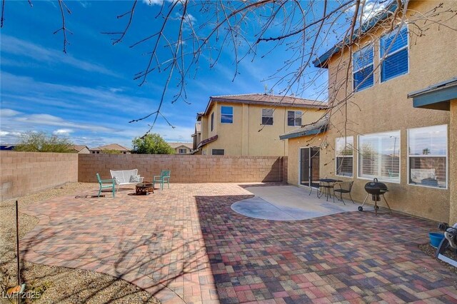 view of patio with area for grilling, a fire pit, and a fenced backyard