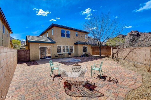 rear view of property featuring stucco siding, a patio, and a fenced backyard