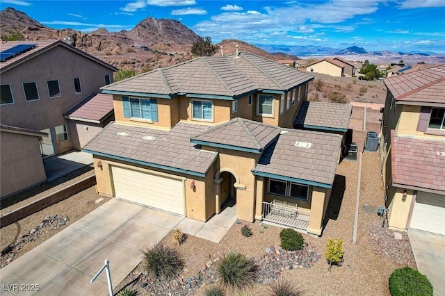 view of front of home with concrete driveway, stucco siding, a mountain view, an attached garage, and a tile roof