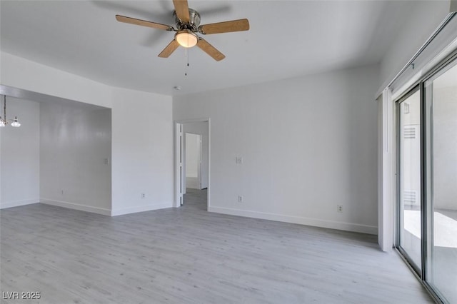 spare room with a healthy amount of sunlight, ceiling fan with notable chandelier, and light wood-style floors