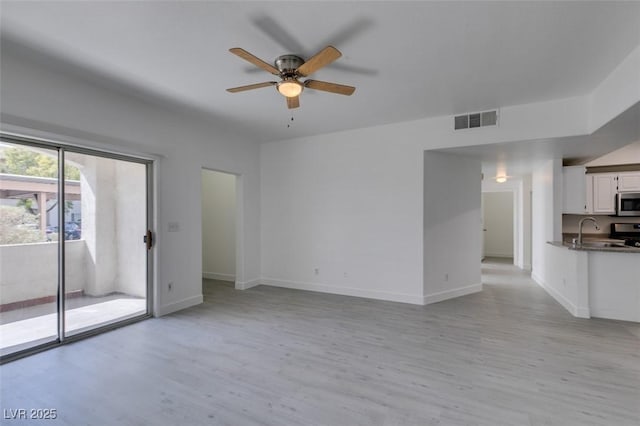 unfurnished living room with visible vents, light wood-style flooring, a ceiling fan, a sink, and baseboards