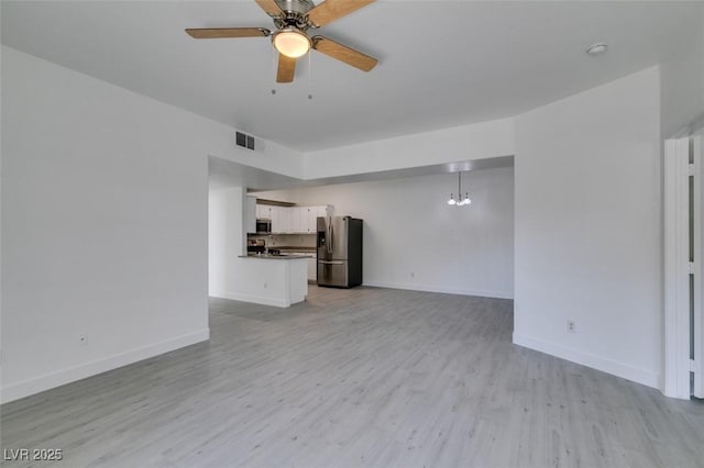 unfurnished living room featuring visible vents, light wood-style flooring, ceiling fan with notable chandelier, and baseboards