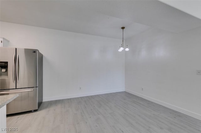 unfurnished dining area with baseboards, light wood-style floors, and an inviting chandelier