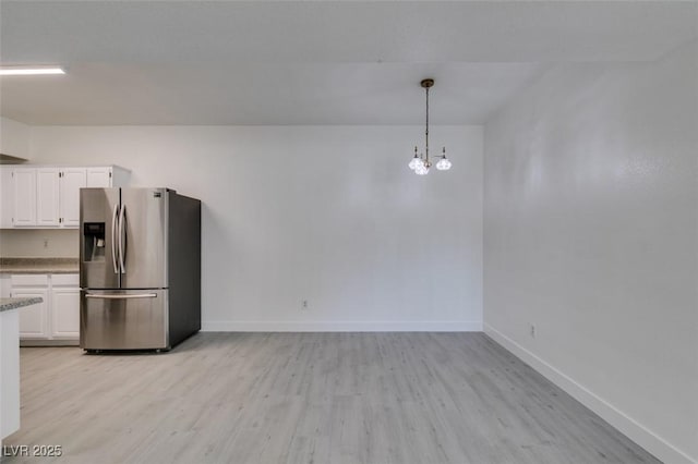 kitchen with white cabinets, stainless steel fridge with ice dispenser, light wood-type flooring, and baseboards