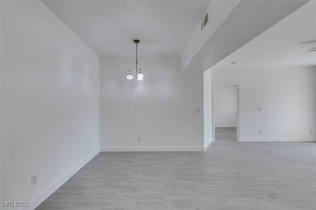 spare room featuring a notable chandelier, baseboards, visible vents, and light wood-type flooring