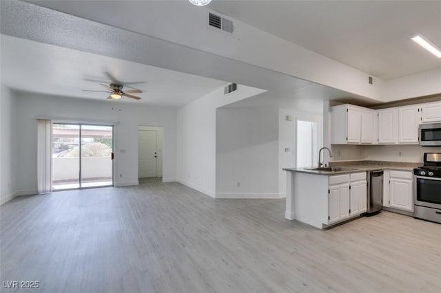 kitchen with a sink, stainless steel appliances, open floor plan, and white cabinetry