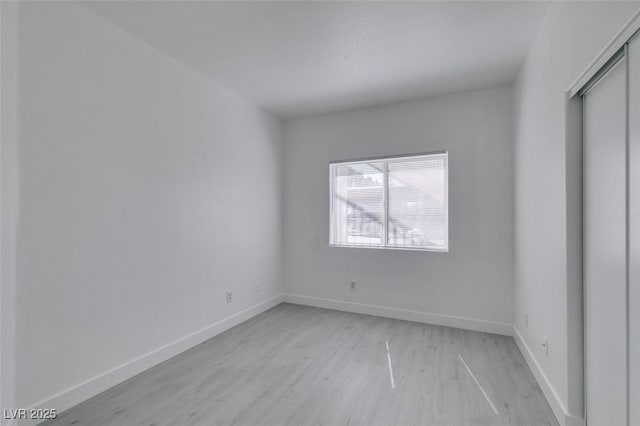 unfurnished bedroom with a closet, baseboards, and light wood finished floors