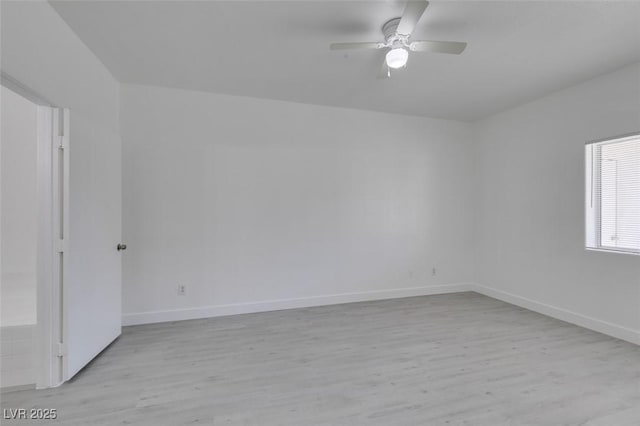 spare room featuring a ceiling fan, light wood-style floors, and baseboards