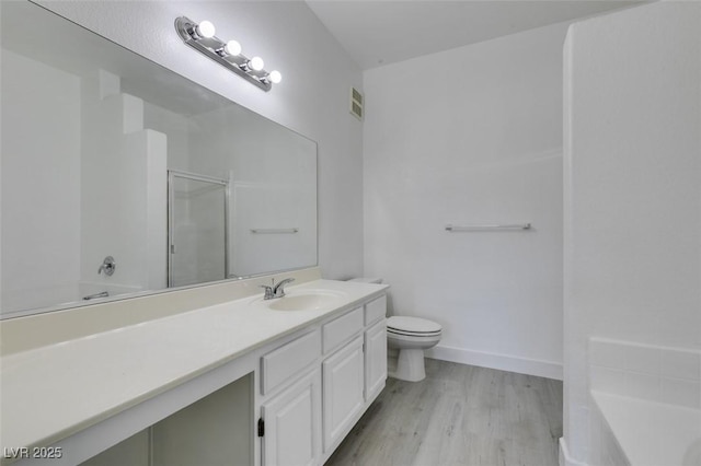 bathroom featuring vanity, wood finished floors, visible vents, an enclosed shower, and toilet