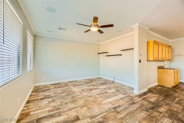 unfurnished room with visible vents, ornamental molding, ceiling fan, and wood finished floors