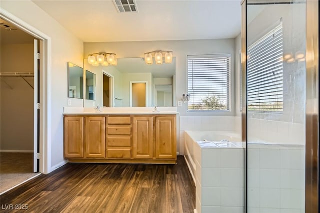 bathroom featuring a sink, visible vents, wood finished floors, and a bath