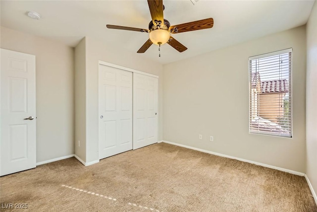 unfurnished bedroom featuring a ceiling fan, baseboards, a closet, and carpet floors