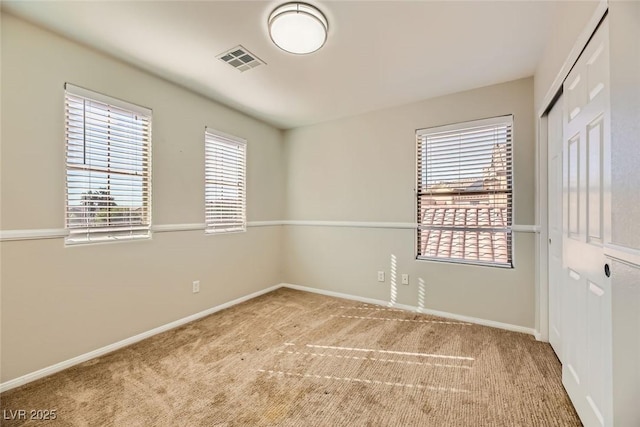 carpeted spare room with baseboards and visible vents