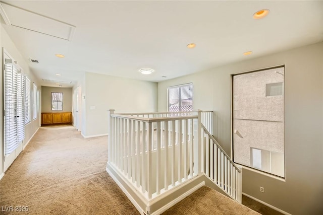 hall with recessed lighting, baseboards, an upstairs landing, and light colored carpet