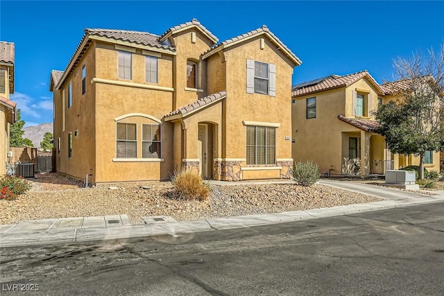 mediterranean / spanish home featuring stucco siding, fence, central AC unit, and a tiled roof