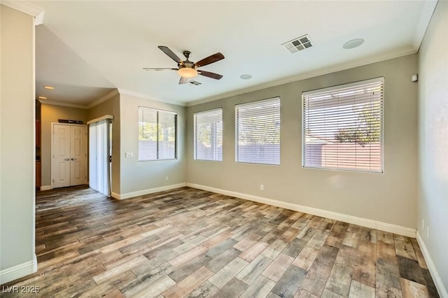 empty room with visible vents, ornamental molding, baseboards, and wood finished floors