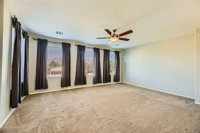 carpeted spare room featuring visible vents, baseboards, and a ceiling fan