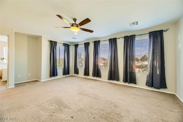 carpeted empty room featuring a ceiling fan, visible vents, and baseboards