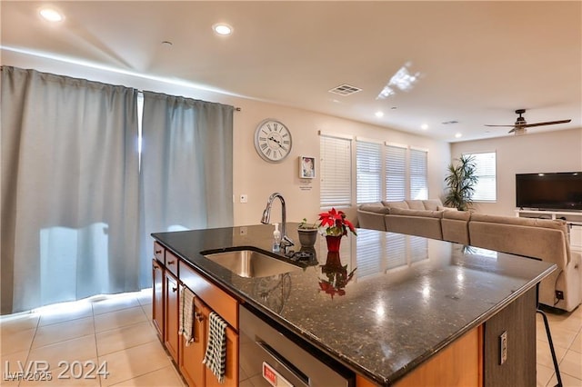 kitchen with light tile patterned floors, visible vents, a center island with sink, and a sink