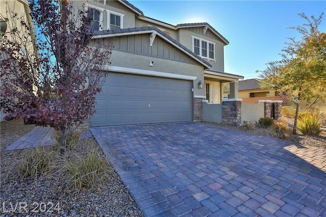 craftsman house featuring stone siding, stucco siding, decorative driveway, and a garage