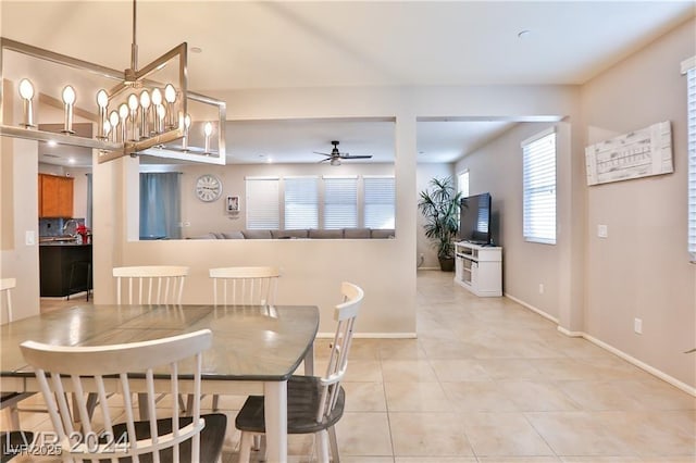 dining space featuring light tile patterned floors, ceiling fan with notable chandelier, and baseboards