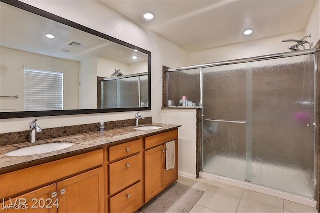 bathroom featuring a sink, double vanity, a shower stall, and tile patterned flooring