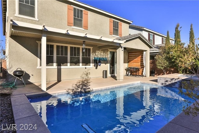 rear view of property with a patio area, an outdoor pool, and stucco siding