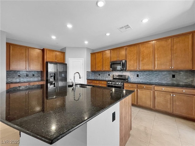 kitchen with visible vents, a sink, stainless steel appliances, a large island, and brown cabinets