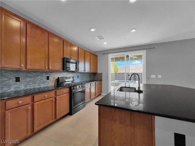 kitchen featuring visible vents, a sink, tasteful backsplash, stainless steel appliances, and dark stone counters