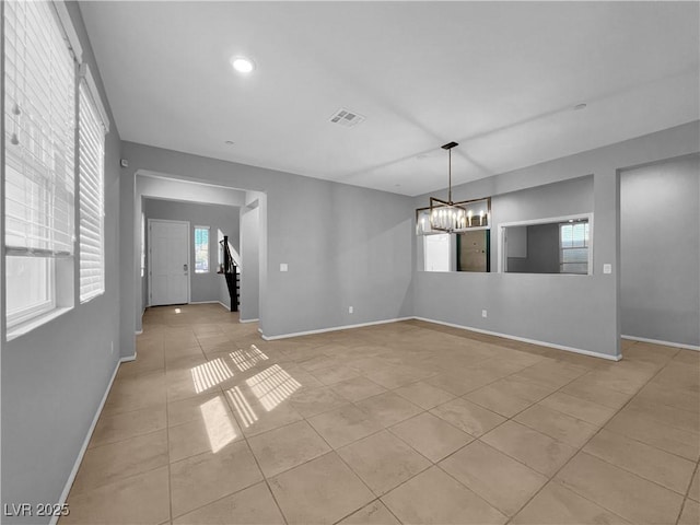 unfurnished dining area featuring visible vents, baseboards, and a notable chandelier