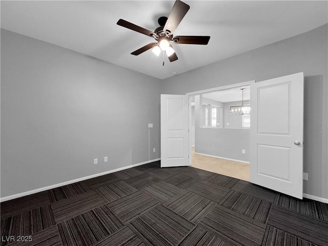 unfurnished bedroom with baseboards, carpet, and ceiling fan with notable chandelier