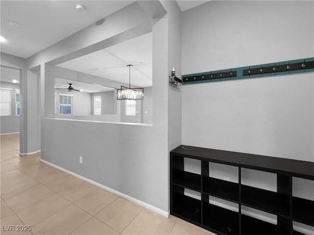 interior space with baseboards and ceiling fan with notable chandelier