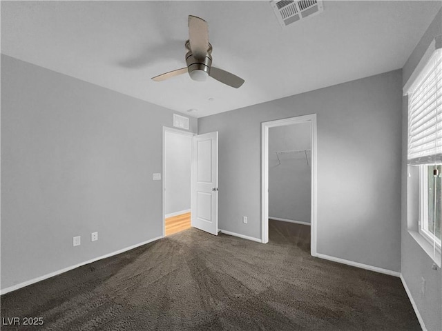 unfurnished bedroom featuring a spacious closet, carpet flooring, baseboards, and visible vents